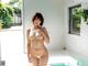 A naked asian woman standing in a room next to a pool.