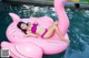 A woman in a pink bikini laying on an inflatable flamingo.