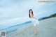 A woman in a white dress standing on a beach.