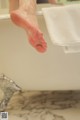 A woman's feet in a bathtub with a towel on the edge.