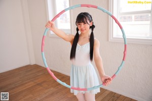 A young woman holding a hula hoop in her hands.