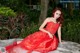 A woman in a red dress sitting on a rock.