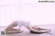 A woman in a white bodysuit is doing a yoga pose.